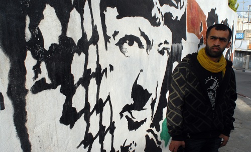 Muhannad Al Azzeh in front of his Arafat portrait in Beit Suheir